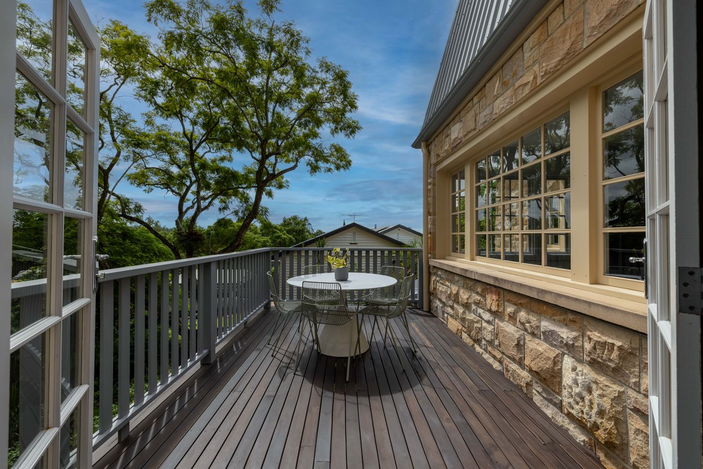 Timber deck with balustrade beside a sandstone home