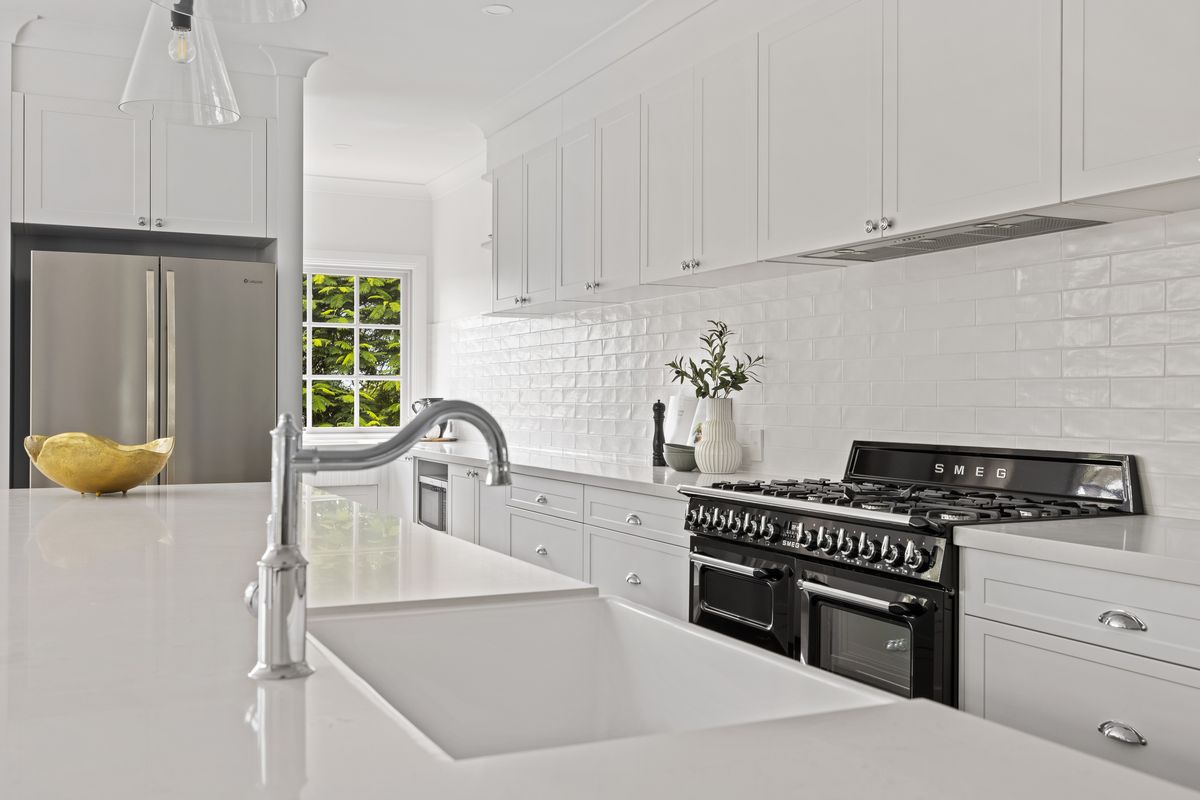 White kitchen with island bench and farmhouse sink